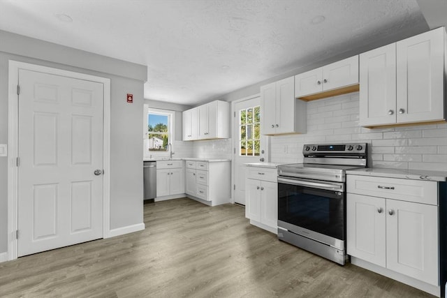 kitchen featuring tasteful backsplash, white cabinetry, a sink, light countertops, and stainless steel appliances