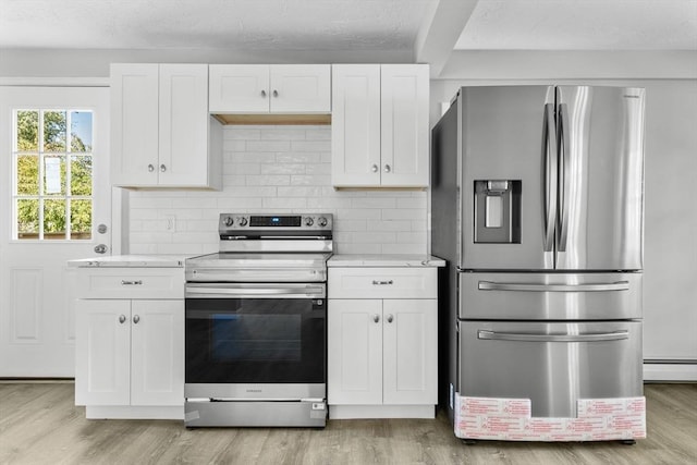 kitchen with decorative backsplash, appliances with stainless steel finishes, light wood finished floors, and white cabinets