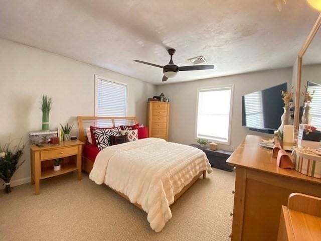 carpeted bedroom featuring a ceiling fan and visible vents