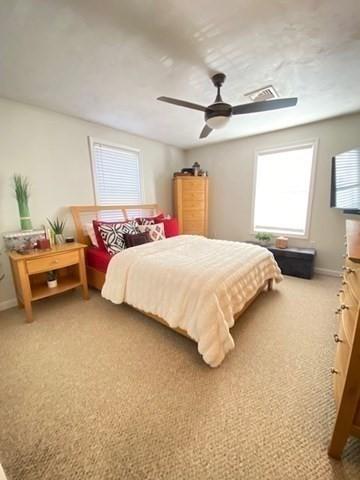 carpeted bedroom featuring a ceiling fan, visible vents, and baseboards