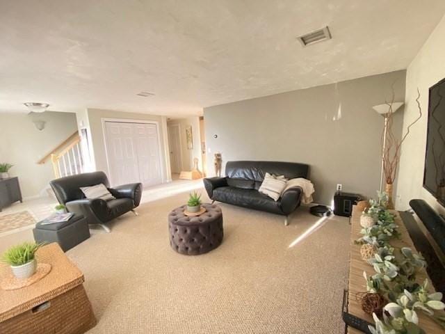 living area with carpet floors, stairway, and visible vents