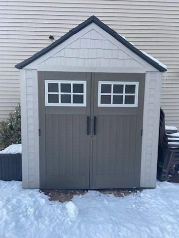 snow covered structure with a shed and an outdoor structure