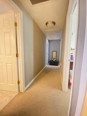 corridor with carpet, tile patterned floors, attic access, and baseboards