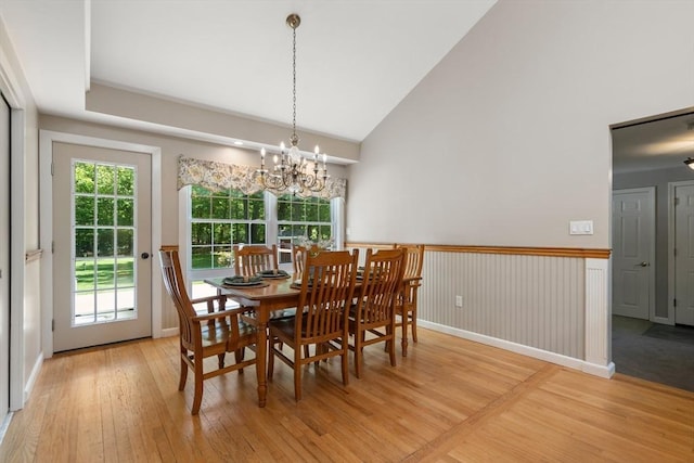 dining room with light wood finished floors, a chandelier, and high vaulted ceiling