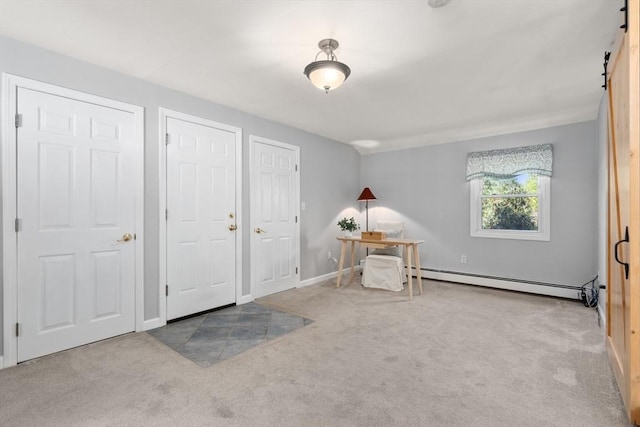 unfurnished bedroom featuring a baseboard radiator, a barn door, carpet, and baseboards