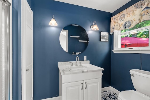 bathroom featuring toilet, vanity, and baseboards