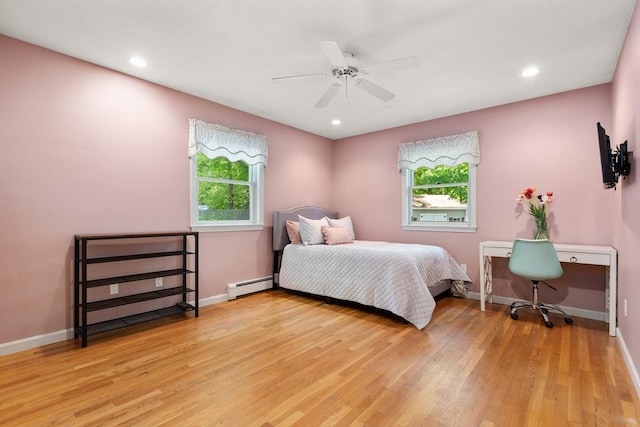bedroom with a baseboard radiator, multiple windows, light wood-type flooring, and recessed lighting