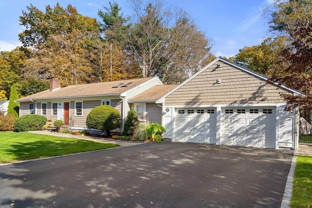 ranch-style house featuring asphalt driveway, a garage, a chimney, and a front yard
