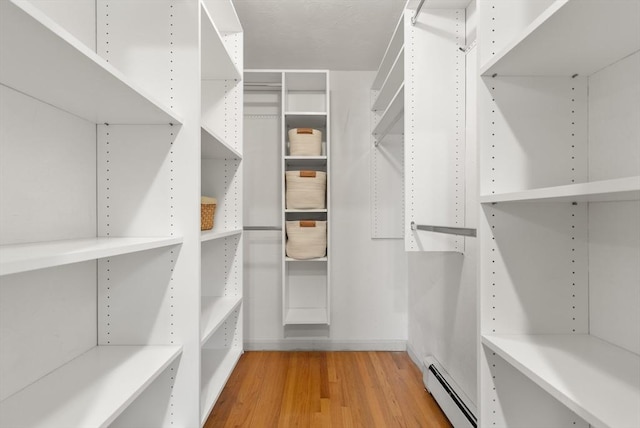 walk in closet featuring baseboard heating and light wood-type flooring