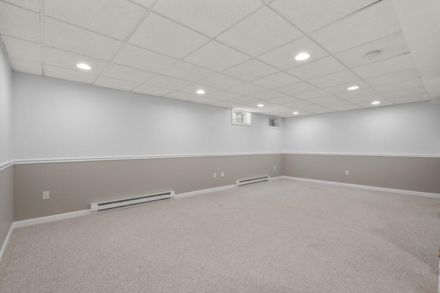 below grade area with baseboard heating, recessed lighting, carpet floors, baseboards, and a paneled ceiling
