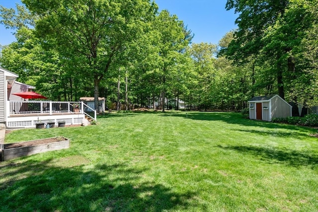 view of grassy yard featuring a shed, an outdoor structure, and a deck