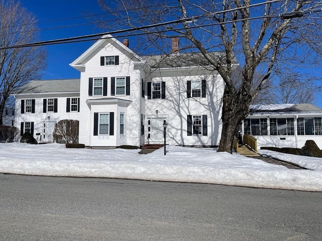 view of front facade with entry steps and a sunroom