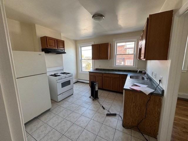 kitchen with light tile patterned flooring, white appliances, a baseboard radiator, and sink