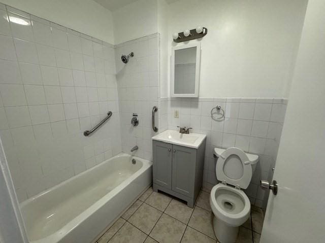 full bathroom with tile patterned floors, toilet, tile walls, vanity, and tiled shower / bath combo