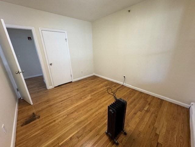 empty room with a baseboard heating unit and wood-type flooring