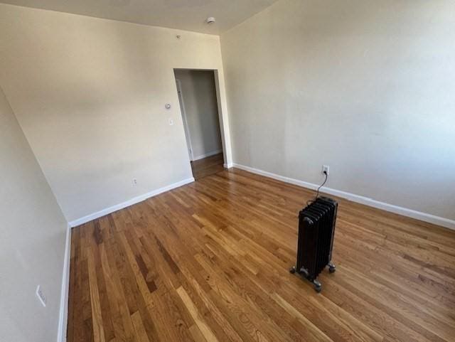 unfurnished room with hardwood / wood-style flooring and radiator