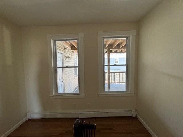 spare room featuring a baseboard radiator and dark hardwood / wood-style floors