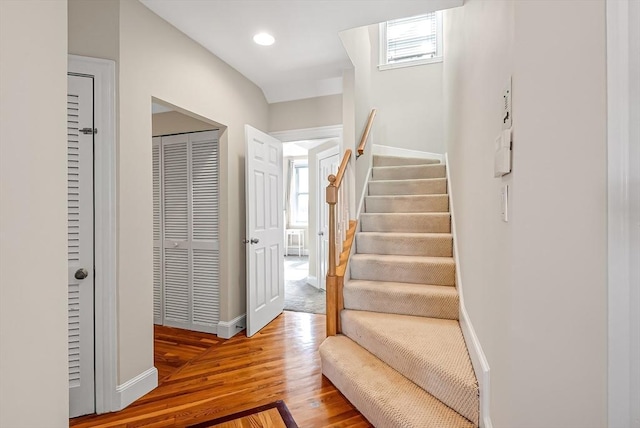 staircase featuring recessed lighting, plenty of natural light, wood finished floors, and baseboards