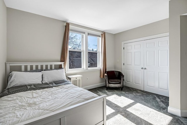 bedroom with a closet, dark carpet, and baseboards