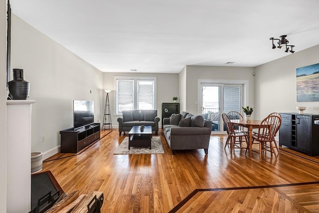 living room with light wood-style floors, baseboards, and a wealth of natural light