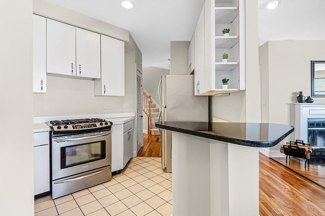 kitchen with light wood finished floors, white cabinets, appliances with stainless steel finishes, a peninsula, and open shelves