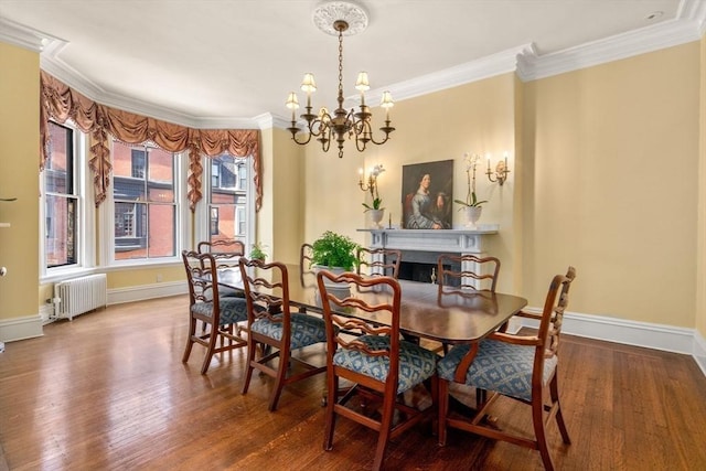 dining space featuring a chandelier, radiator heating unit, wood finished floors, and crown molding