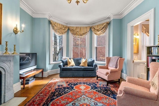 sitting room featuring ornamental molding, a healthy amount of sunlight, baseboards, and wood finished floors