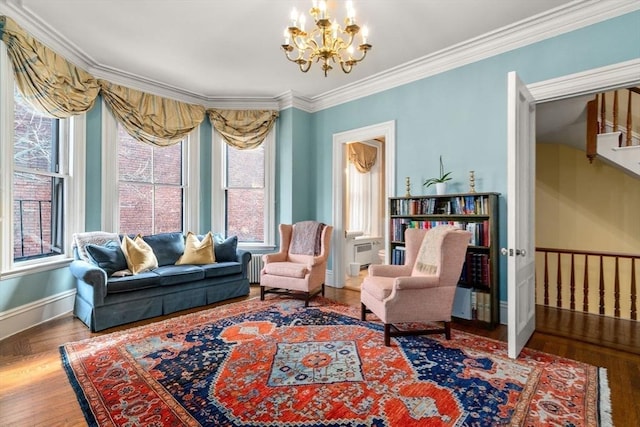 sitting room featuring baseboards, radiator heating unit, wood finished floors, crown molding, and a notable chandelier