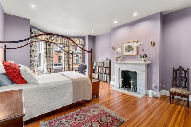 bedroom with a fireplace with flush hearth, recessed lighting, baseboards, and wood finished floors