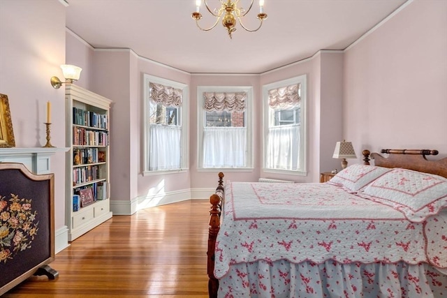 bedroom featuring baseboards, a notable chandelier, ornamental molding, and wood finished floors