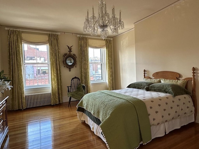 bedroom with radiator, a notable chandelier, ornamental molding, and wood finished floors