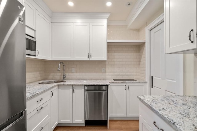 kitchen with stainless steel appliances, white cabinets, a sink, and tasteful backsplash