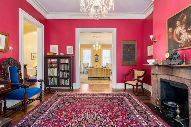 sitting room with a fireplace with flush hearth, wood finished floors, a notable chandelier, and ornamental molding