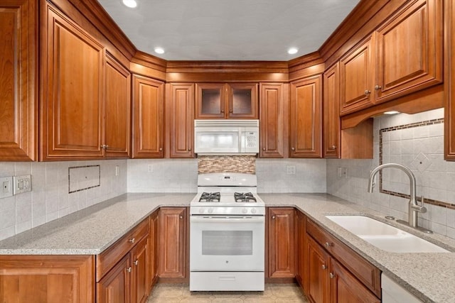 114 Byron St, Boston, MA 02128 - kitchen featuring white appliances, a sink, brown cabinetry, tasteful backsplash, and light stone countertops