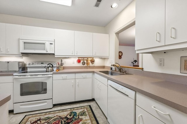 kitchen with light tile patterned floors, white cabinetry, sink, and white appliances