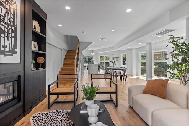 living room with built in shelves and light hardwood / wood-style floors