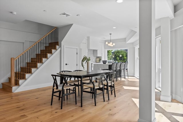 dining space featuring light hardwood / wood-style floors and an inviting chandelier