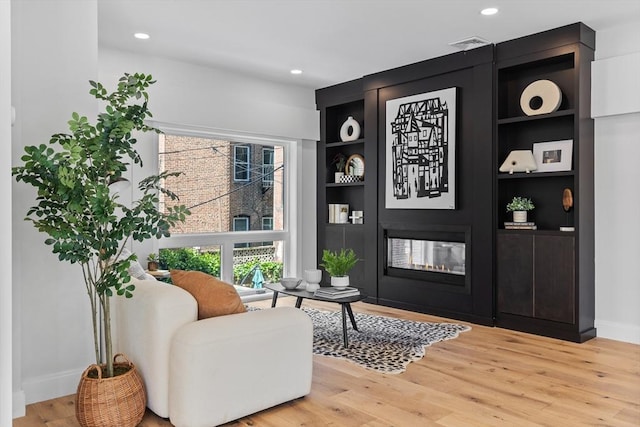 living area with a fireplace, built in features, and hardwood / wood-style floors