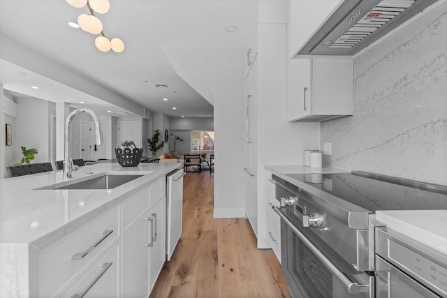 kitchen with stainless steel appliances, custom range hood, light wood-type flooring, white cabinetry, and sink