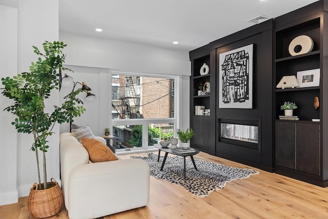 sitting room featuring hardwood / wood-style floors and built in shelves