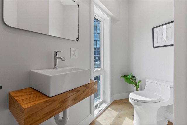 bathroom with toilet, hardwood / wood-style floors, and sink