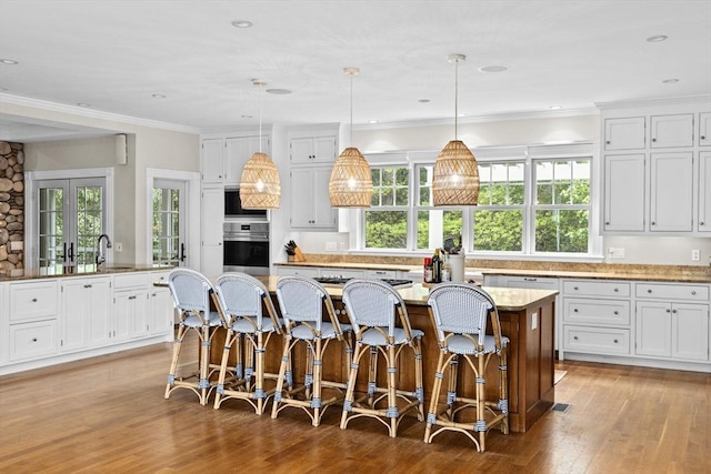 54 Garrison Dr, Scituate, MA 02066 - kitchen featuring appliances with stainless steel finishes, a kitchen island, light wood-style flooring, a kitchen bar, and white cabinets
