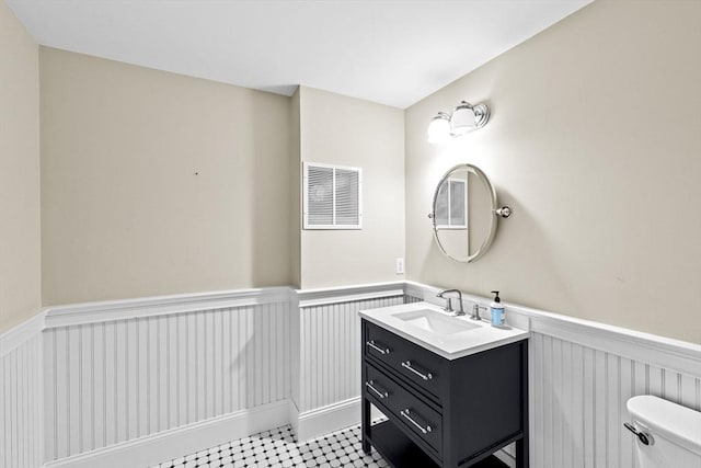 54 Garrison Dr, Scituate, MA 02066 - bathroom featuring a wainscoted wall, vanity, toilet, and a decorative wall