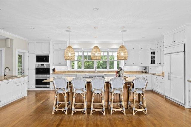 54 Garrison Dr, Scituate, MA 02066 - kitchen with built in appliances, a sink, a kitchen island, wood finished floors, and a breakfast bar