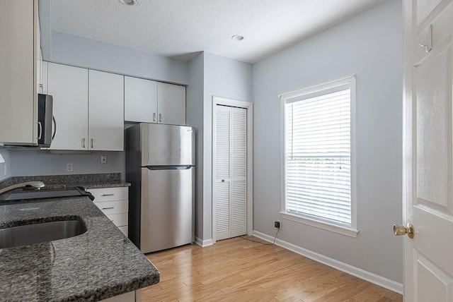 109 Bradford Commons Ln Unit 109, Braintree, MA 02184 - kitchen featuring stainless steel appliances, light wood-style flooring, dark stone counters, white cabinetry, and a textured ceiling