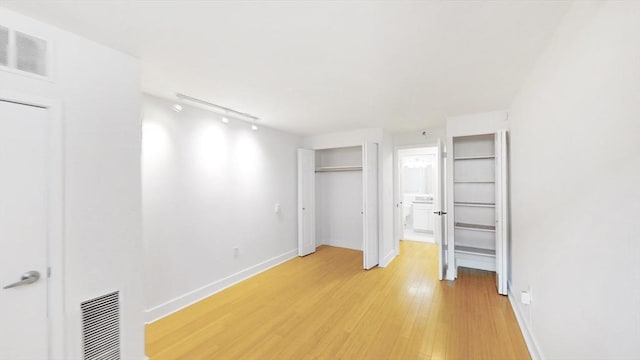 42 8th St Unit 2110, Boston, MA 02129 - unfurnished bedroom with light wood finished floors, rail lighting, baseboards, and ensuite bath