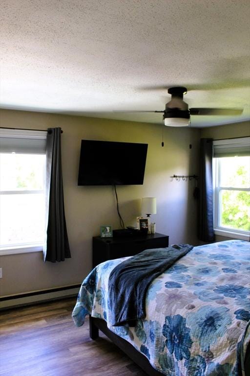 13 Laurana Ln, Hadley, MA 01035 - bedroom featuring wood finished floors, a textured ceiling, a baseboard heating unit, and a ceiling fan