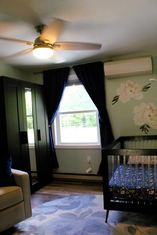 13 Laurana Ln, Hadley, MA 01035 - bedroom featuring an AC wall unit, baseboard heating, and a ceiling fan