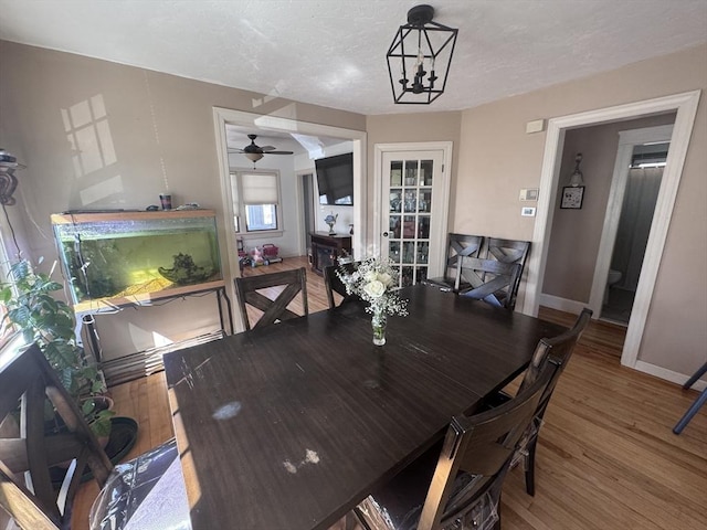 dining room featuring baseboards, a textured ceiling, an inviting chandelier, and wood finished floors