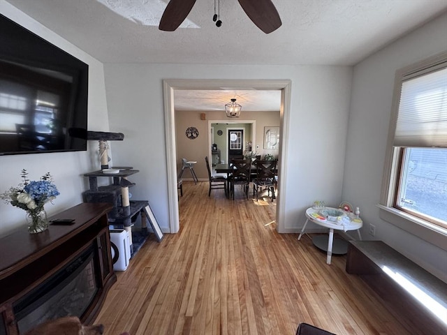 interior space with baseboards, ceiling fan, a textured ceiling, and light wood-style floors